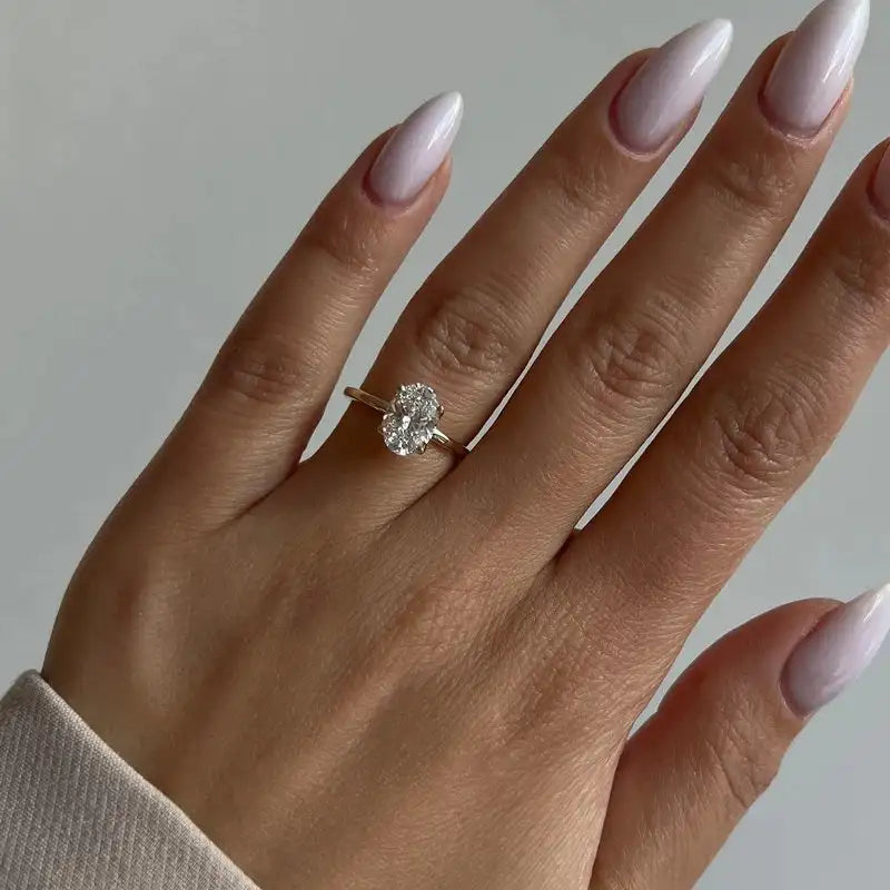 A delicate gold band ring featuring a prominent oval-cut diamond centered on the finger.