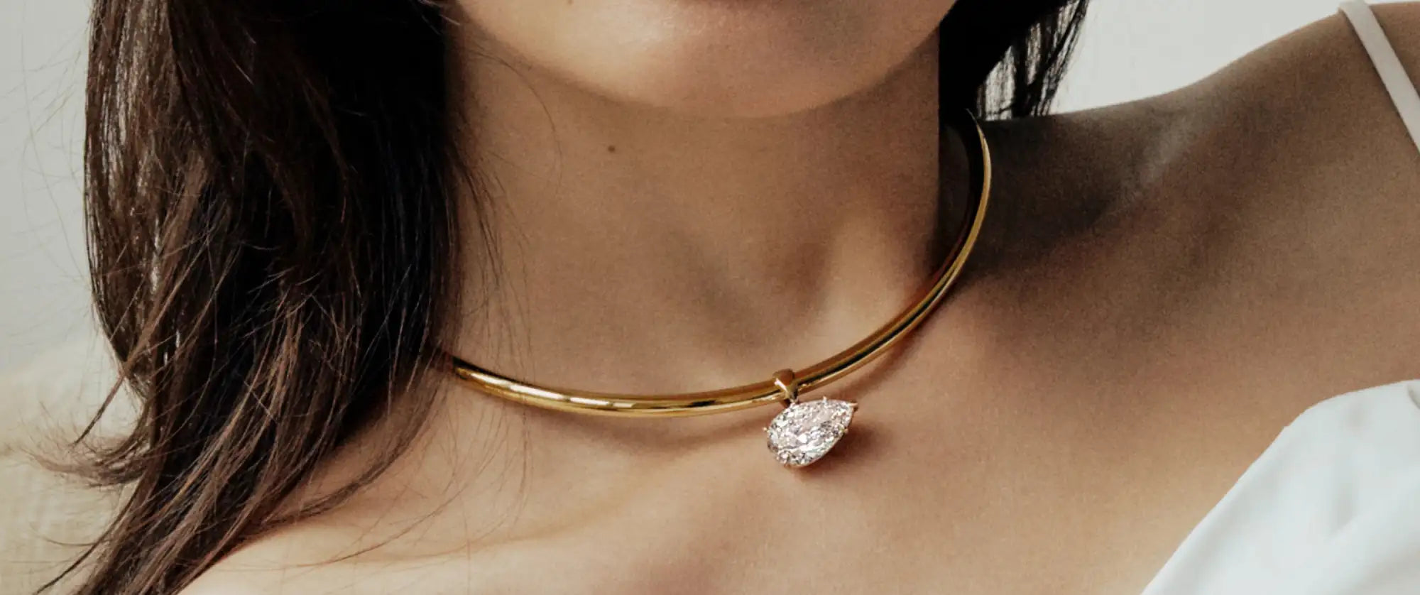 Gold necklace with a diamond pendant worn by a person