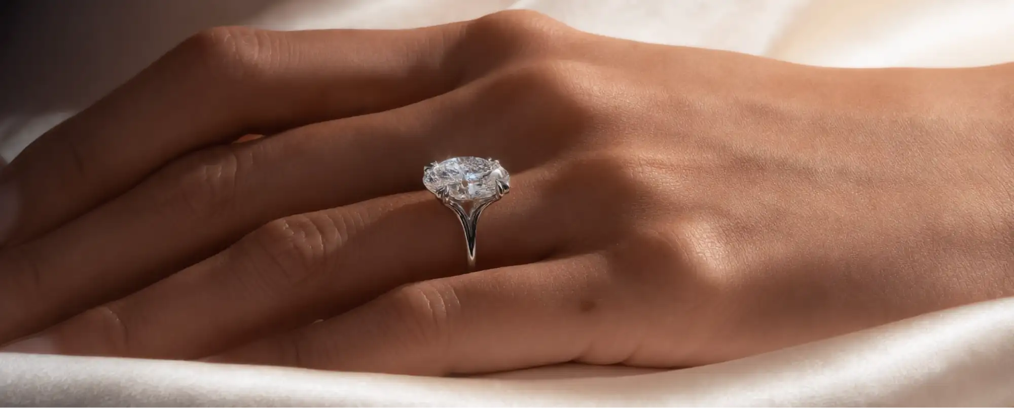 Hand wearing a diamond ring on a soft fabric background