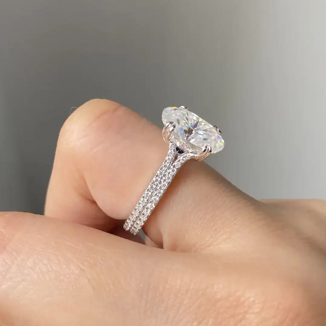 A sparkling oval-cut diamond ring with a pave-set band, set in a sleek silver-toned metal.