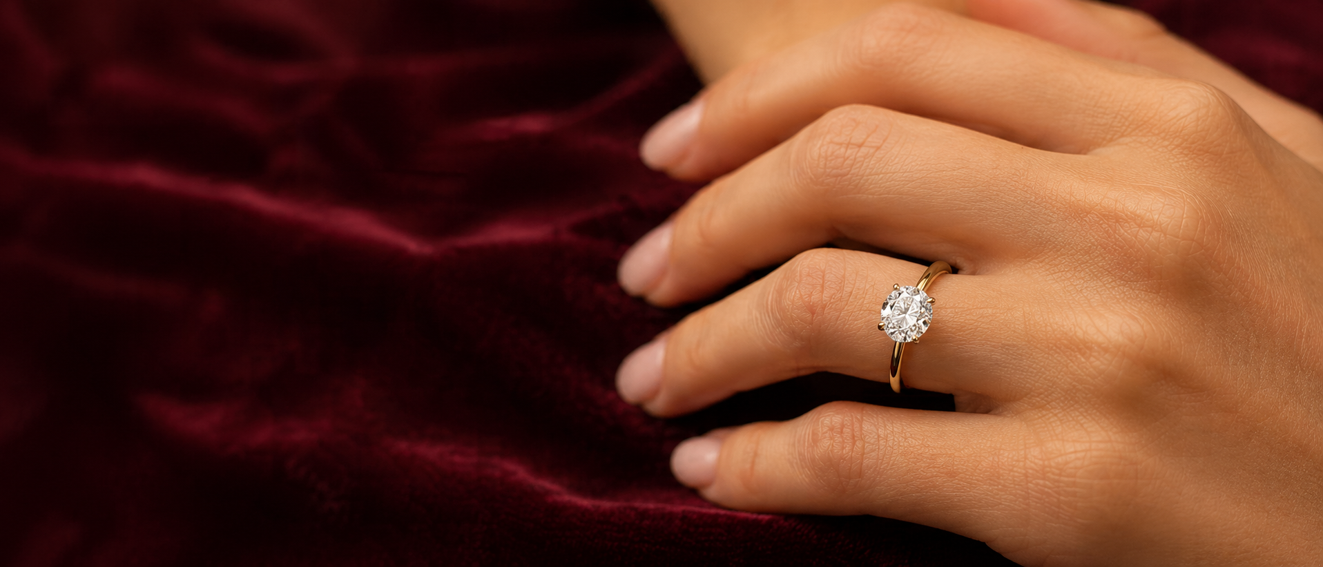 Close-up of a hand wearing a diamond ring on a dark background