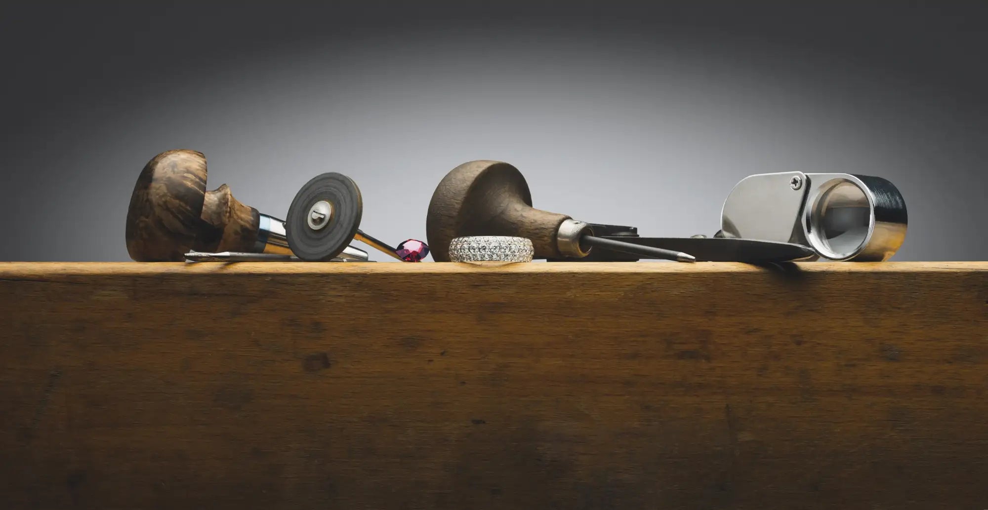 A polished silver jeweler’s loupe with a black handle and circular magnifying lens.