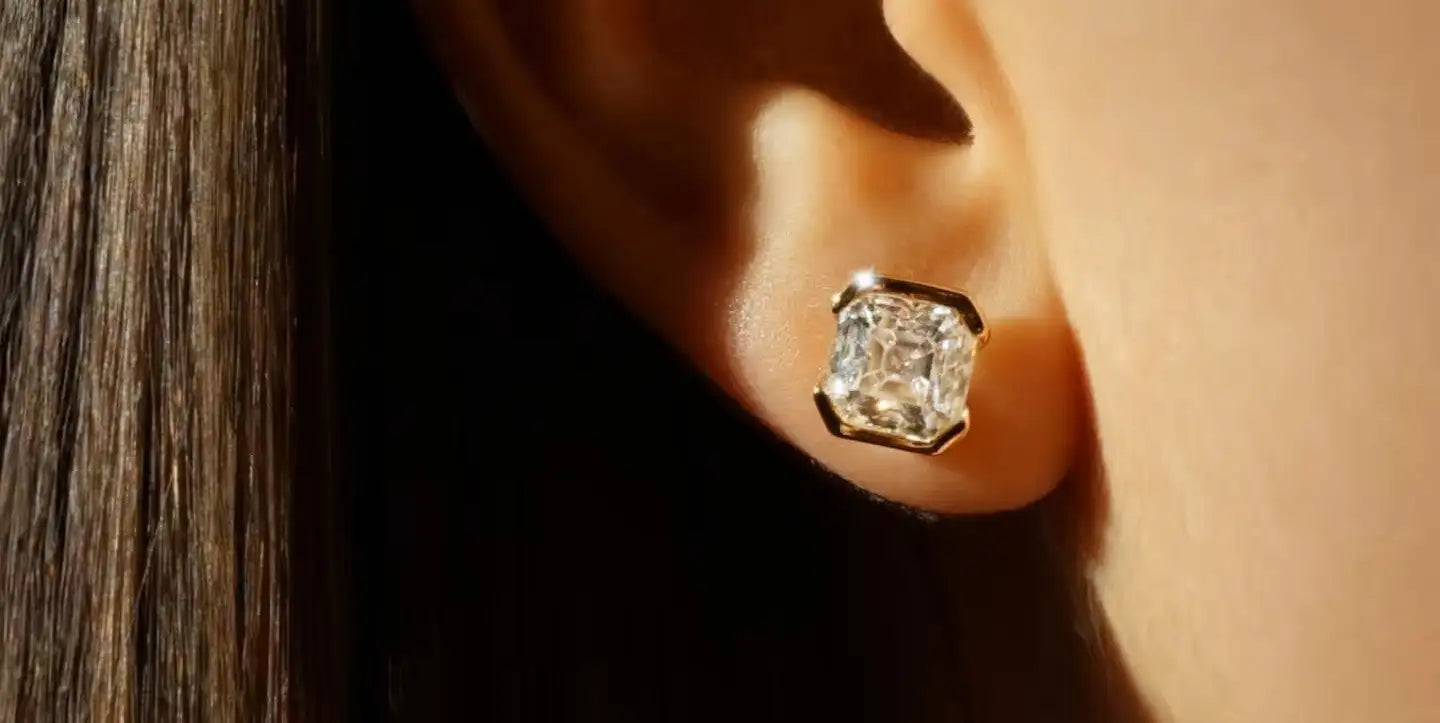 Close-up of a diamond earring worn on an ear with a blurred background