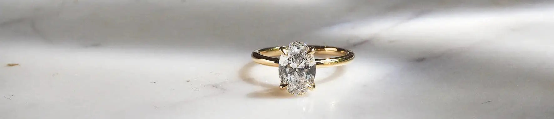 Gold ring with a diamond on a marble surface