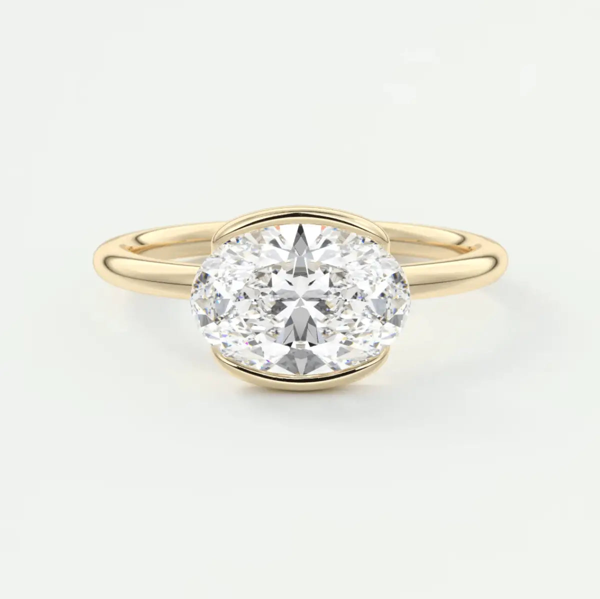 18k yellow gold oval diamond engagement ring with a bezel setting.