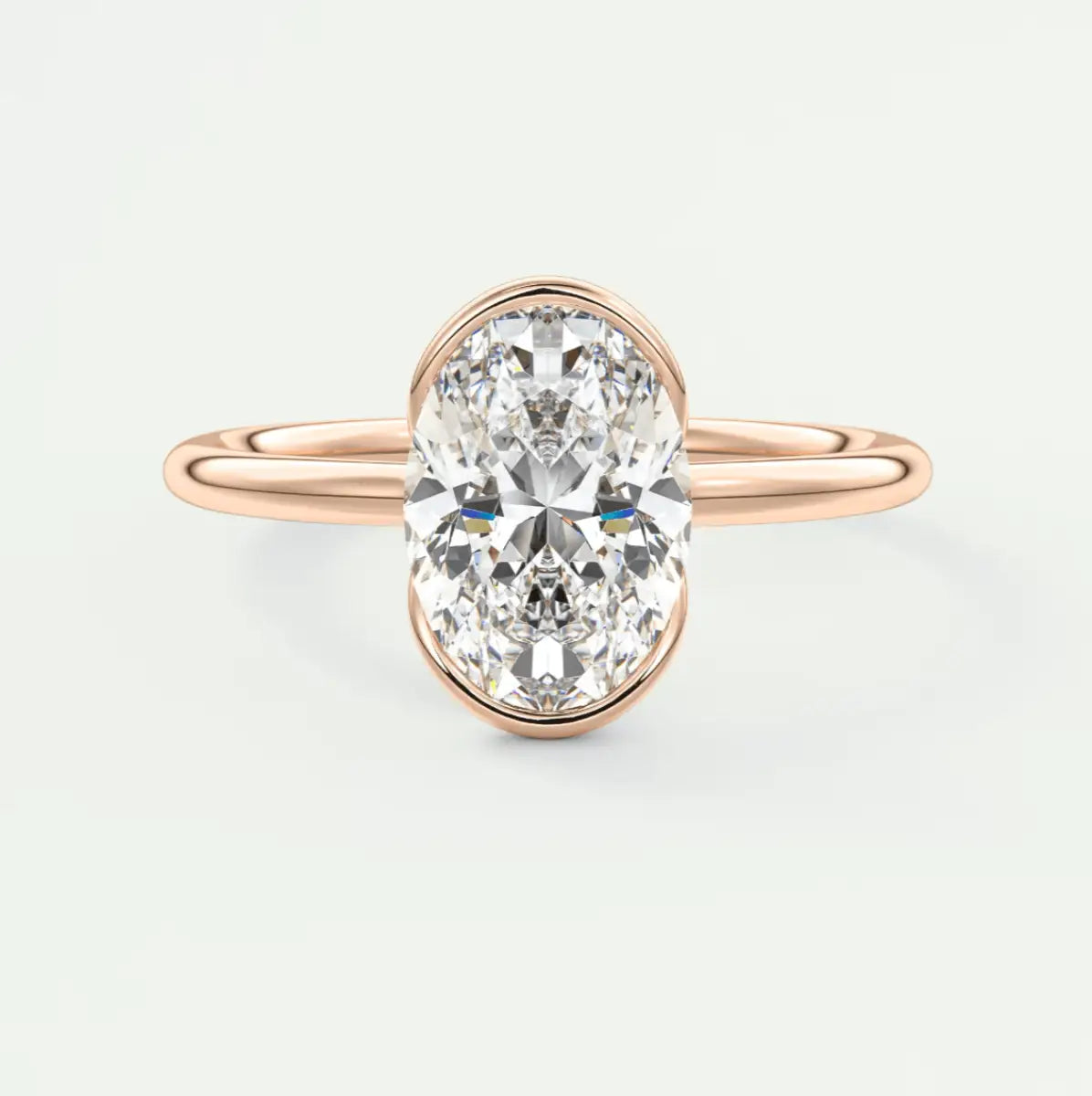 Rose gold oval diamond engagement ring with a bezel setting.