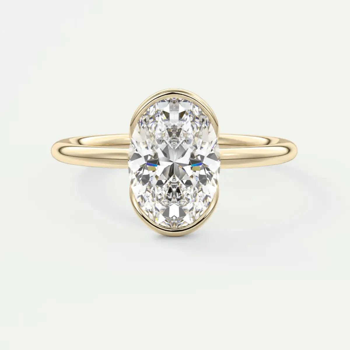 18k yellow gold oval diamond engagement ring with a bezel setting.