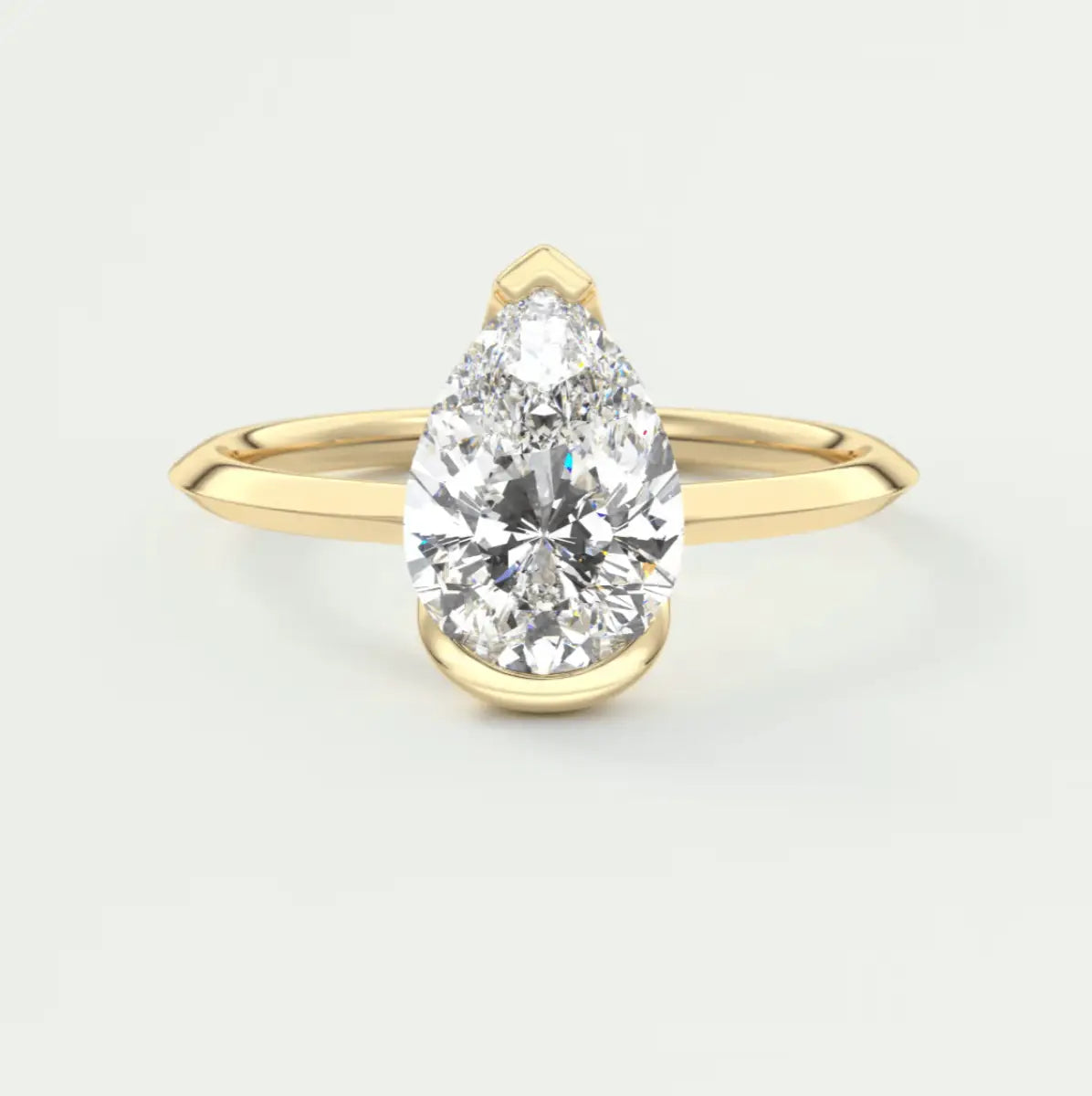 Pear-shaped diamond engagement ring with yellow gold band, elegant design.