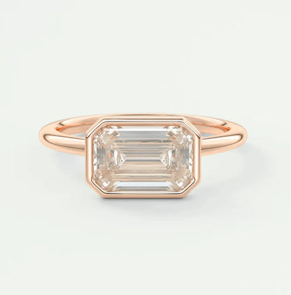18-karat rose gold emerald-cut diamond ring with a bezel setting.